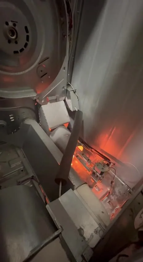 The igniter and burner area cycling during an open-cabinet test without normal assembled airflow.
